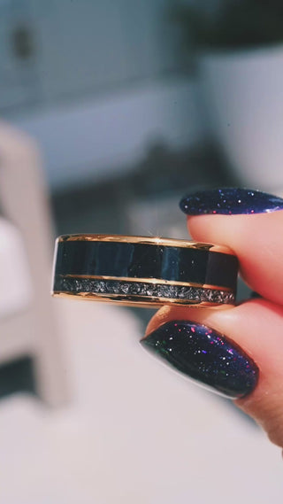 Video of the Black Onyx & Meteorite Men's Wedding Band in Yellow Gold Tungsten (8mm) by Aquamarise held in daylight, black onyx beside a crushed meteorite channel