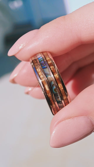 Hand holding ocean inspired beach wedding band with paua shell
