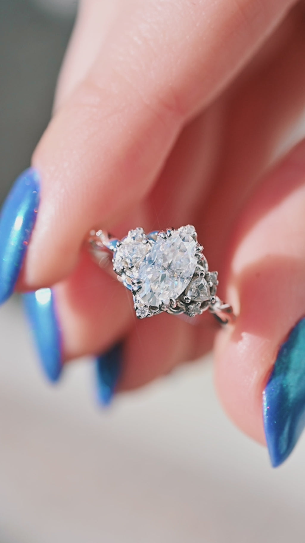 Hand holding diamond ring with an oval-shaped center stone