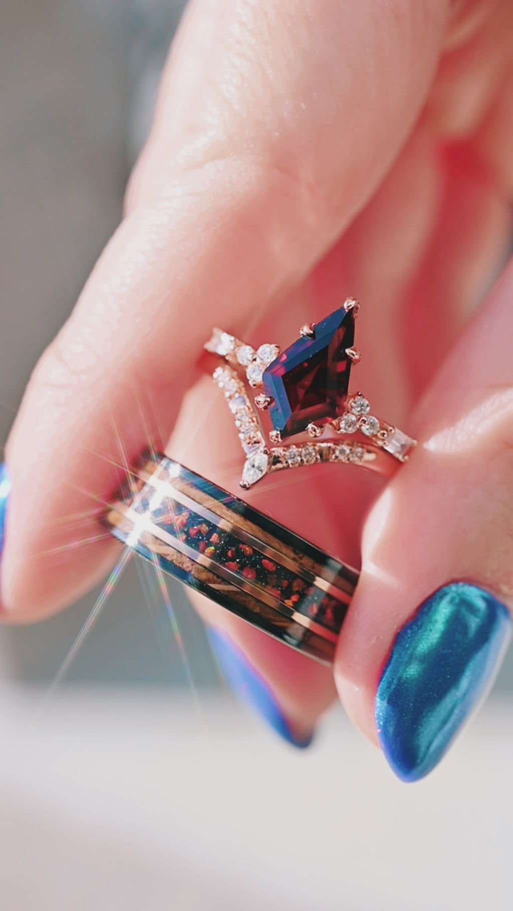 Hand holding his and hers garnet engagement ring and opal wedding band