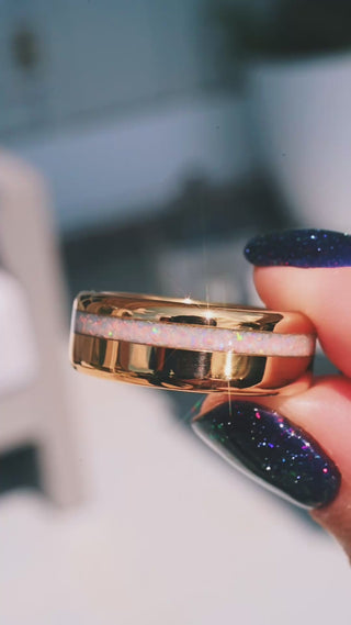 Video of the White Fire Opal Men's Wedding Band in Yellow Gold Tungsten (8mm) by Aquamarise held in daylight, showing the crushed white fire opal inlay