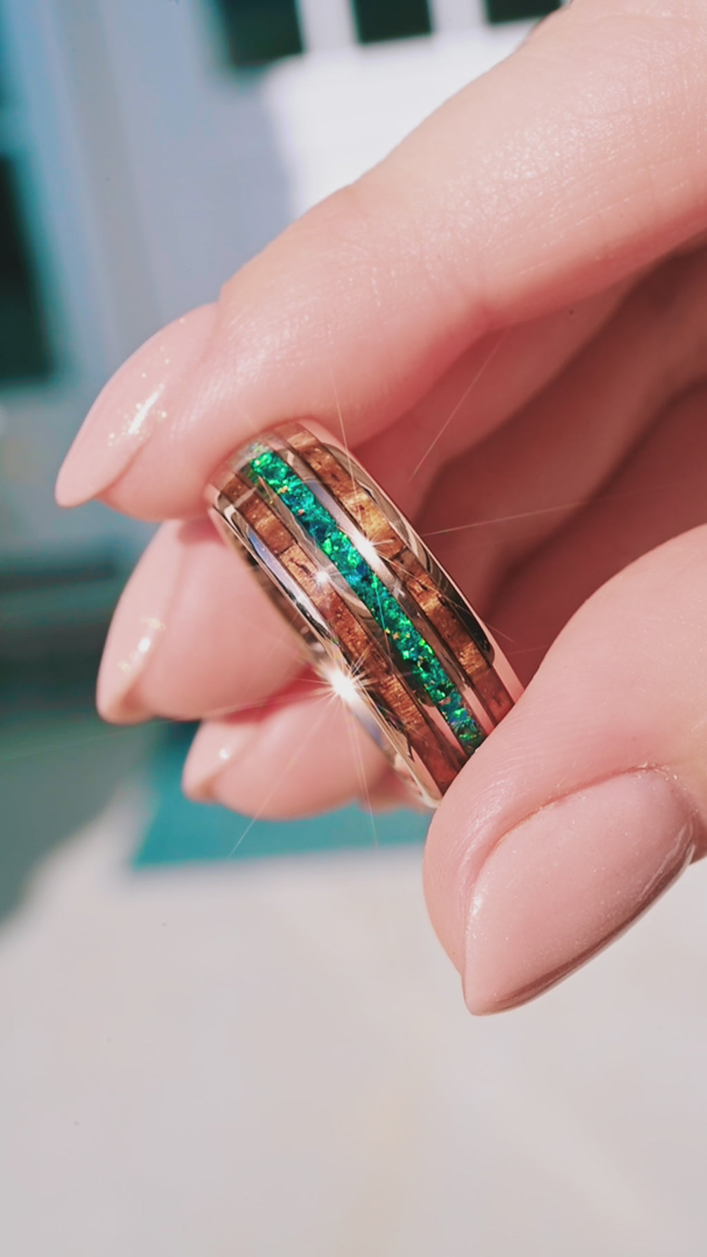 Hand holding blue green peacock opal tungsten ring