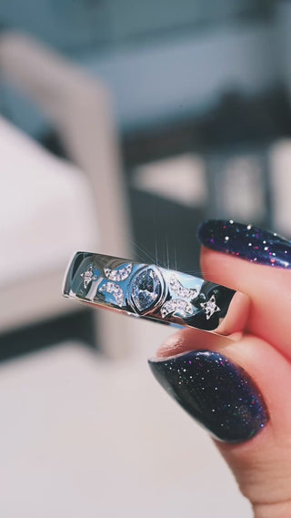 Video of the Gray Moissanite Celestial Wedding Band in Sterling Silver (6mm) by Aquamarise held in daylight, showing the marquise gray moissanite and star details