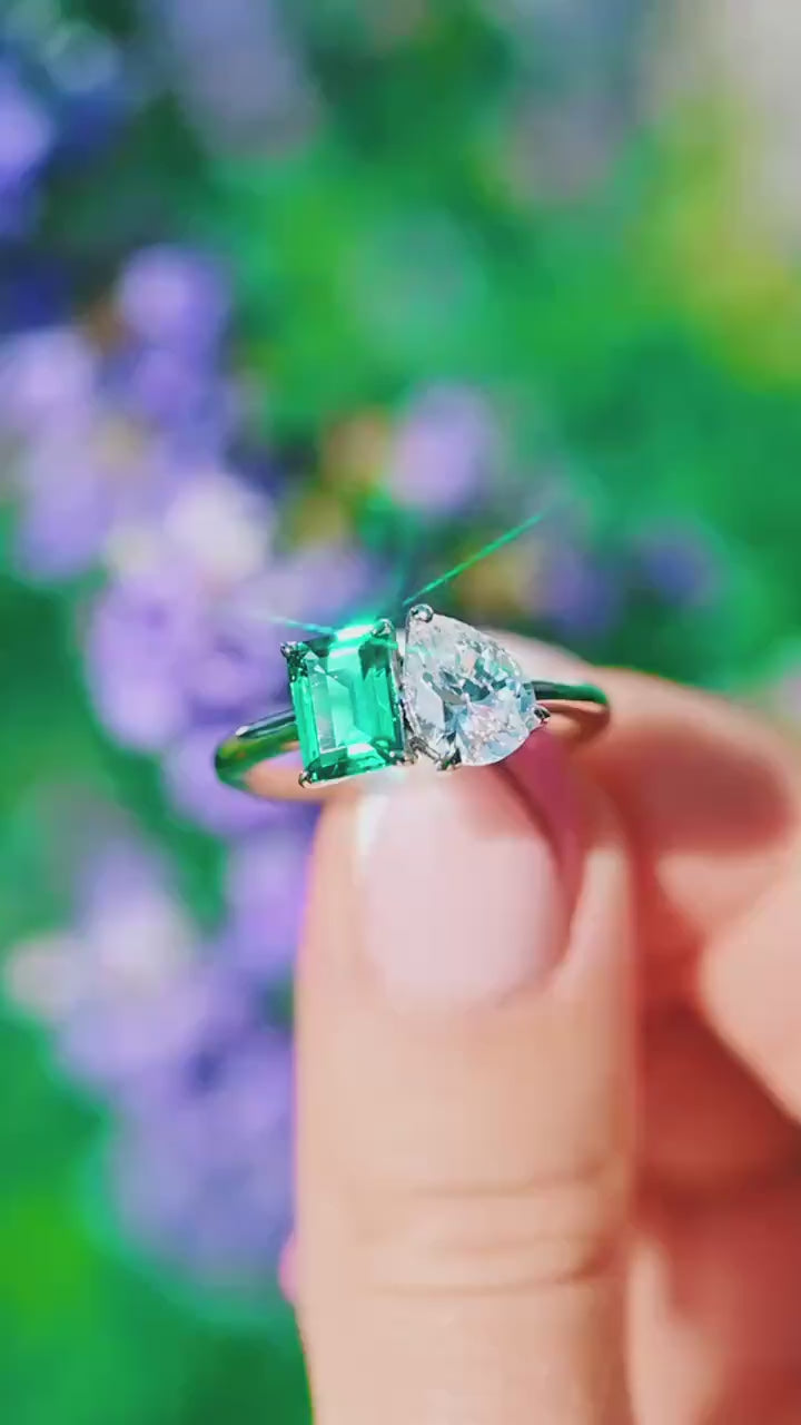 Video of a toi et moi emerald and moissanite ring by Aquamarise, shown in motion
