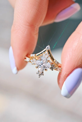 Gold ring with a star-shaped diamond held between fingers with light purple nail polish.