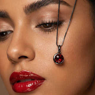 Close-up of a woman's face wearing a necklace with a red pendant.