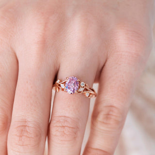 Rose gold ring with a pink gemstone on a hand against a blurred background