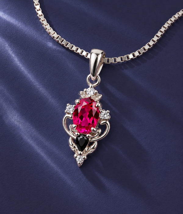 Carmilla lab-grown ruby and black onyx pendant necklace in sterling silver on a box chain, over navy satin, Aquamarise banner