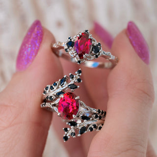 Two silver rings with red gemstones on a hand with purple nail polish.