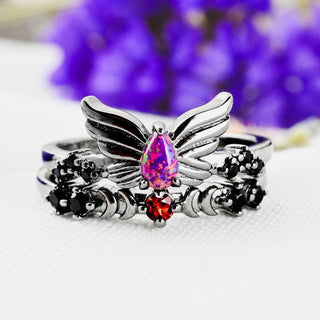 Selene Magenta Opal and Black Onyx wing ring with Padparadscha Sapphire crescent moon band in black ruthenium stacked beside purple flowers