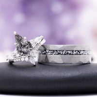 Skye Kite salt and pepper Herkimer diamond ring beside the men's hammered silver tungsten band with a meteorite inlay, on a dark stone