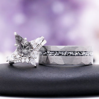 Skye Kite salt and pepper Herkimer diamond ring beside the men's hammered silver tungsten band with a meteorite inlay, on a dark stone