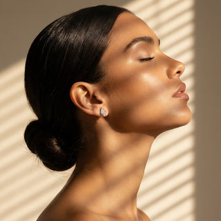 Woman with closed eyes, side profile against a beige wall with shadow patterns