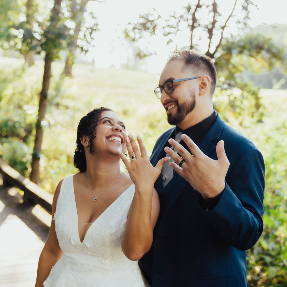 Bride and groom laughing outdoors on their wedding day, the groom wearing a Starry Night® men's wedding band in black tungsten carbide – Aquamarise customer photo