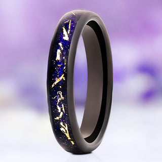 Starry Night Stardust wedding band in black tungsten carbide, 4mm, standing upright with gold leaf flakes scattered through the sparkling midnight-blue sandstone inlay