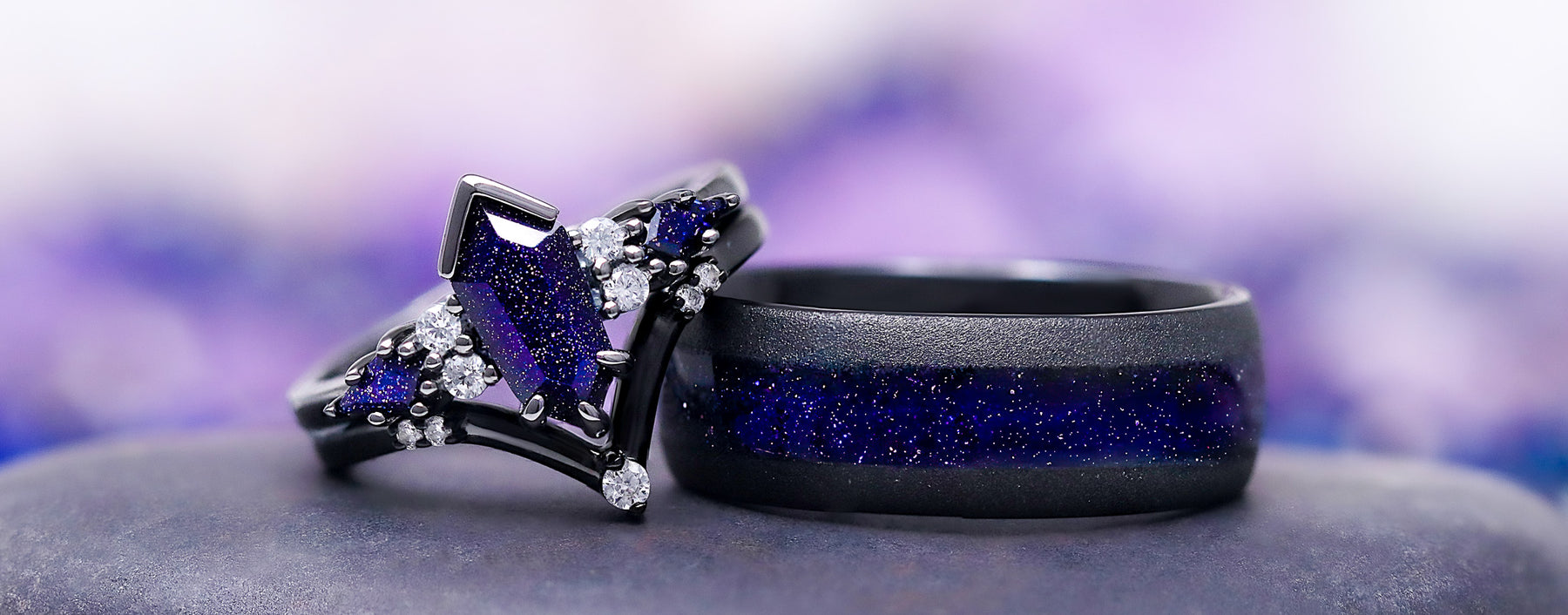 Two black rings with blue accents on a gray surface with a blurred purple and blue background