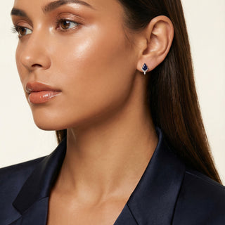 Close-up of a woman wearing a blue earring against a neutral background