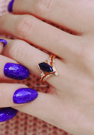 Close-up of hands with purple nail polish and a decorative ring.