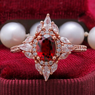 Stella natural red garnet ring in 14K rose gold vermeil with a marquise and round halo, shown on red velvet beside pearls