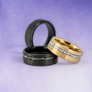 Three rings, two black and one gold, on a purple background