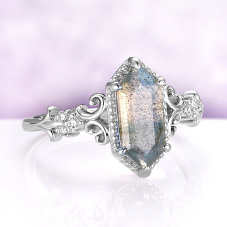 Angled view of the Vesper labradorite ring showing the blue flash across the elongated hexagon and the scroll detail on the shoulders