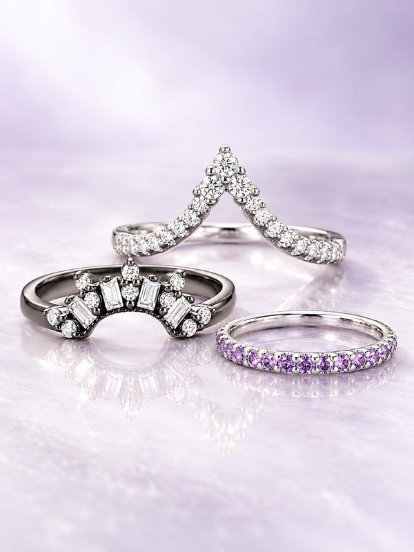 Three women's wedding bands on lilac satin: chevron pave band, black baguette crown band and amethyst eternity band, Aquamarise banner