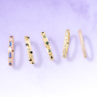 Set of gold rings with gemstones on a light purple background