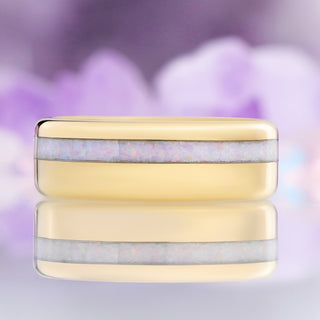 Front view of the 8mm yellow gold tungsten men's wedding band with an offset white fire opal inlay, reflected on a mirror surface