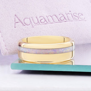 White fire opal and yellow gold tungsten men's band displayed with the Aquamarise suede jewelry pouch