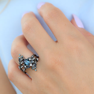 Wisteria black ruthenium leaf ring and matching enhancer worn together, showing the teal accent stones