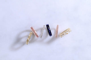 Set of five gold rings with various designs on a light gray background