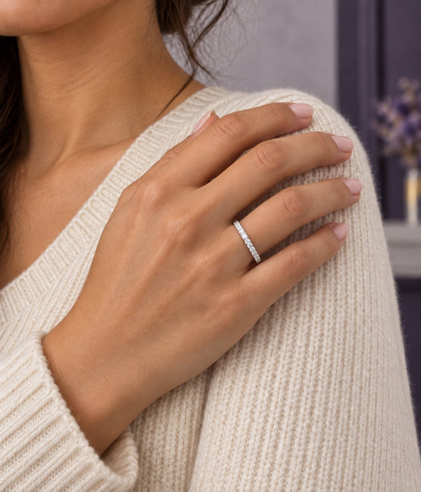 Woman in a cream sweater with her hand on her shoulder wearing a pave eternity wedding band, Aquamarise banner
